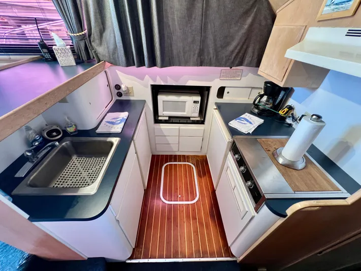White Shark Yacht Photos Pics Compact kitchen in 1988 Hatteras 48 Convertible yacht with sink, microwave, and stove.