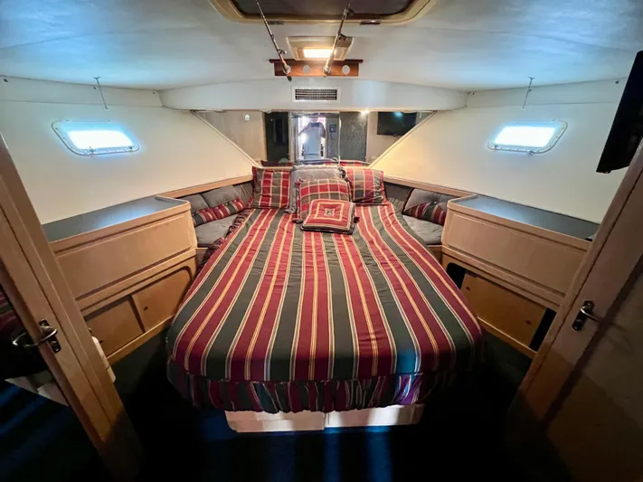White Shark Yacht Photos Pics 1988 Hatteras 48 Convertible cabin with striped bedding and wooden cabinetry.