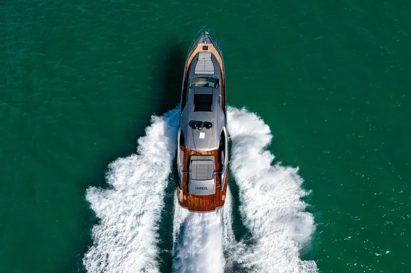 Unreel Yacht Photos Pics 2023 Pershing 7X yacht cruising on turquoise water, aerial view.