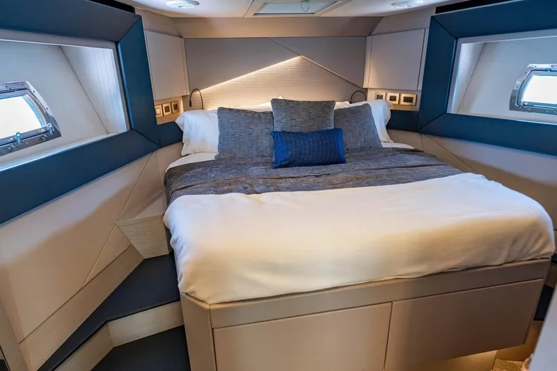 Unreel Yacht Photos Pics Luxurious bedroom interior of 2023 Pershing 7X yacht with modern design and cozy bedding.