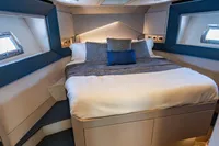 Luxurious bedroom interior of 2023 Pershing 7X yacht with modern design and cozy bedding.
