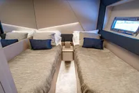 Luxurious twin cabin interior of 2023 Pershing 7X yacht with modern design and window view.