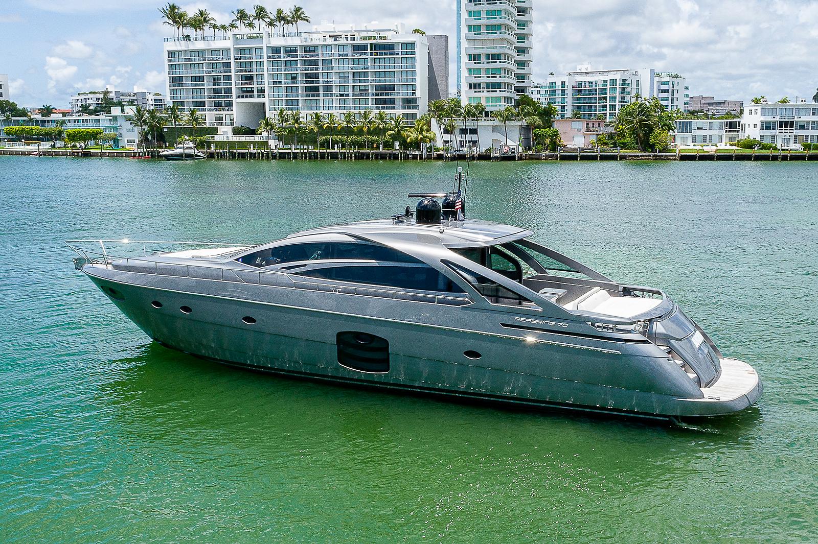 Luxury 2015 Pershing 70 yacht on water, modern buildings in background.