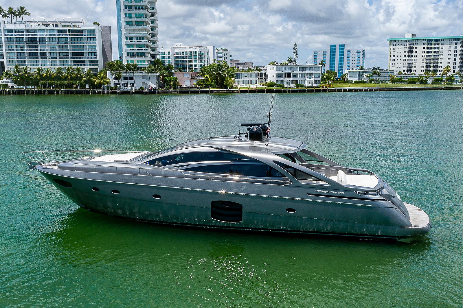2015 Pershing 70 yacht on calm water with modern buildings in the background.