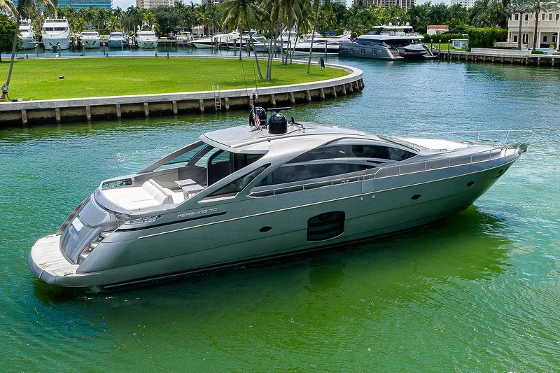 Andiamo Yacht Photos Pics 2015 Pershing 70 yacht cruising in a serene marina with lush greenery.