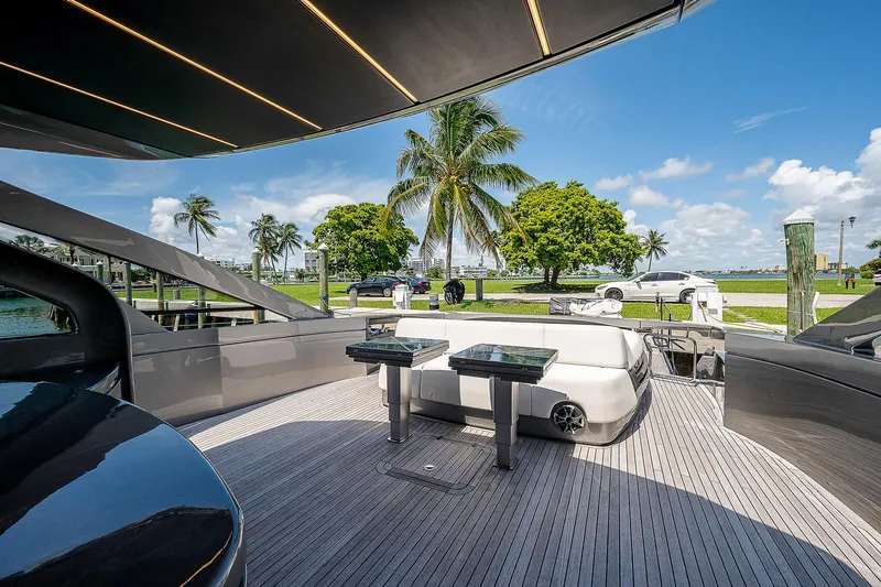 Andiamo Yacht Photos Pics Luxurious 2015 Pershing 70 yacht deck with seating, palm trees, and blue sky backdrop.