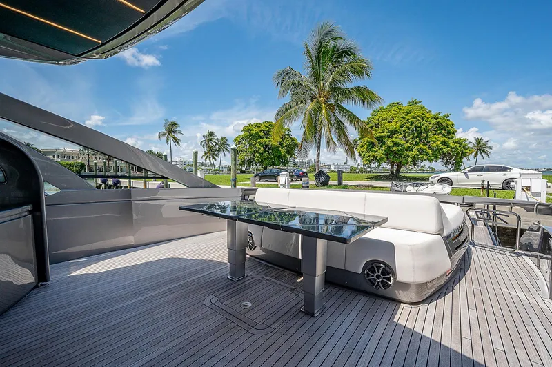 Andiamo Yacht Photos Pics Luxurious 2015 Pershing 70 yacht deck with seating, glass table, and scenic palm tree view.