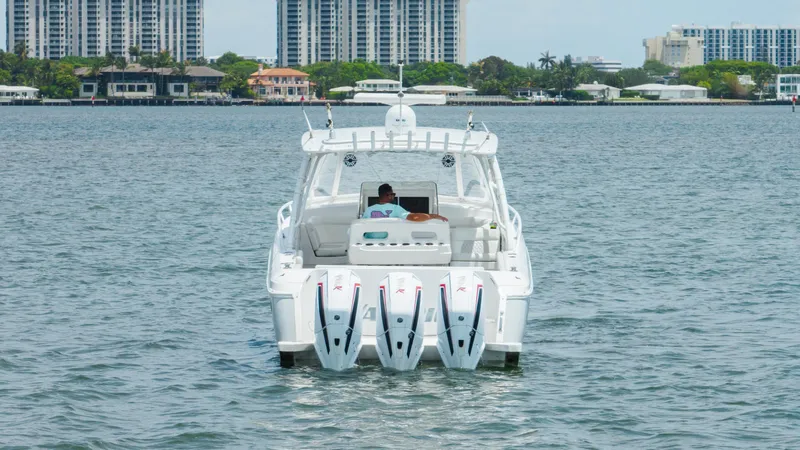 Intrepid Yacht Photos Pics 2013 Intrepid 400 Cuddy boat with triple engines on water, cityscape background.