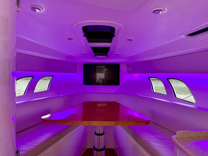 Intrepid Yacht Photos Pics 2013 Intrepid 400 Cuddy interior with purple lighting and a central table.