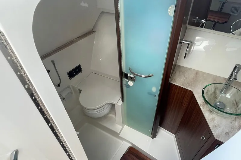 Lady B Yacht Photos Pics 2019 Pursuit DC 365 Dual Console boat bathroom with modern fixtures and frosted glass door.