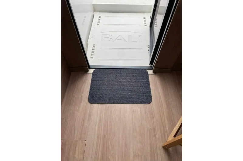 Nia Yacht Photos Pics Interior view of a 2022 Bali 4.6, featuring a wooden floor and entrance mat.