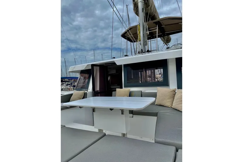 Nia Yacht Photos Pics 2022 Bali 4.6 yacht with outdoor seating and table under cloudy sky.