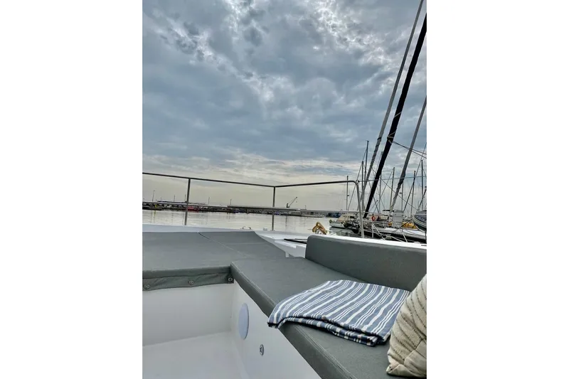 Nia Yacht Photos Pics 2022 Bali 4.6 yacht deck with cushions, moored at a marina under cloudy skies.