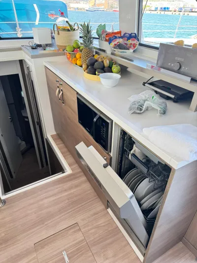 Nia Yacht Photos Pics Modern Bali 4.6 yacht kitchen with open dishwasher, fresh fruits, and ocean view.