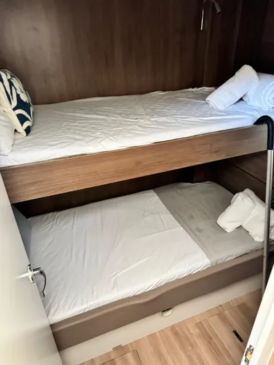 Nia Yacht Photos Pics Bunk beds in a Bali 4.6 yacht cabin, 2022 model, with wooden finish and white bedding.