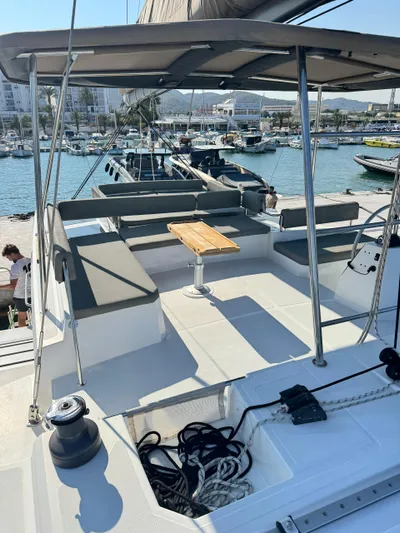 Nia Yacht Photos Pics Luxurious 2022 Bali 4.6 yacht deck with seating and table, docked at marina.
