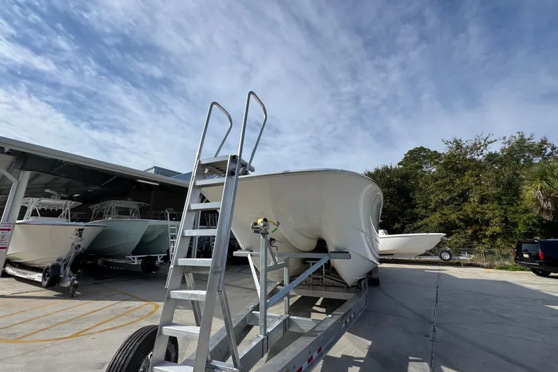  Yacht Photos Pics 2023 Invincible 46 Catamaran on trailer under clear sky, with nearby boats and trees.