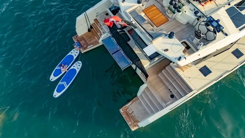 Jack Yacht Photos Pics Aerial view of 2023 McConaghy MC75 yacht with paddleboards on turquoise water.