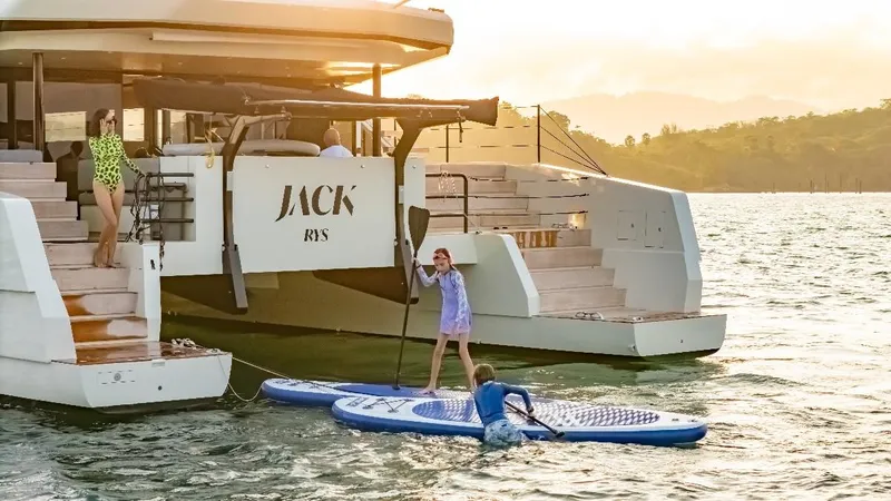 Jack Yacht Photos Pics 2023 McConaghy MC75 yacht with people enjoying paddleboarding at sunset.