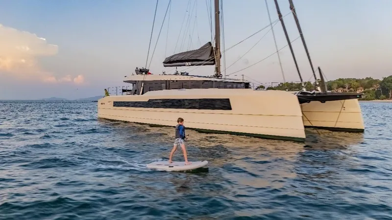 Jack Yacht Photos Pics 2023 McConaghy MC75 catamaran on water with person paddleboarding nearby.