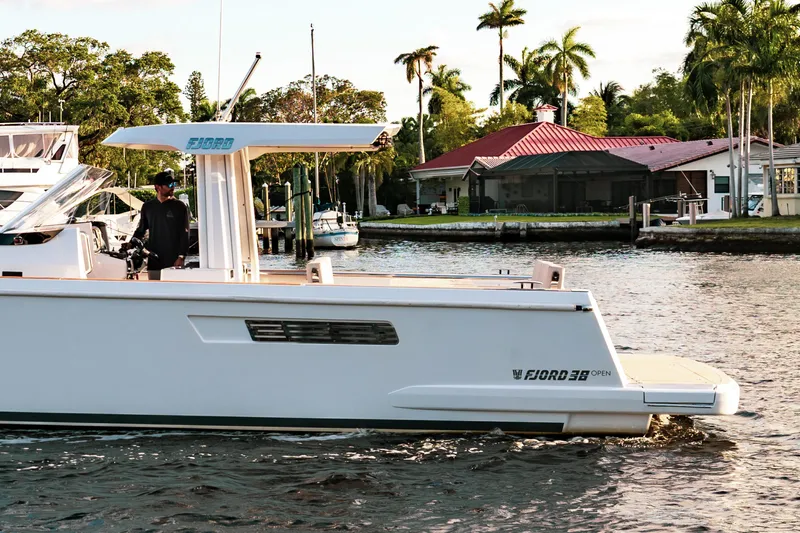 Next Yacht Photos Pics 2022 Fjord 38 Open boat cruising on a scenic waterway with lush greenery.