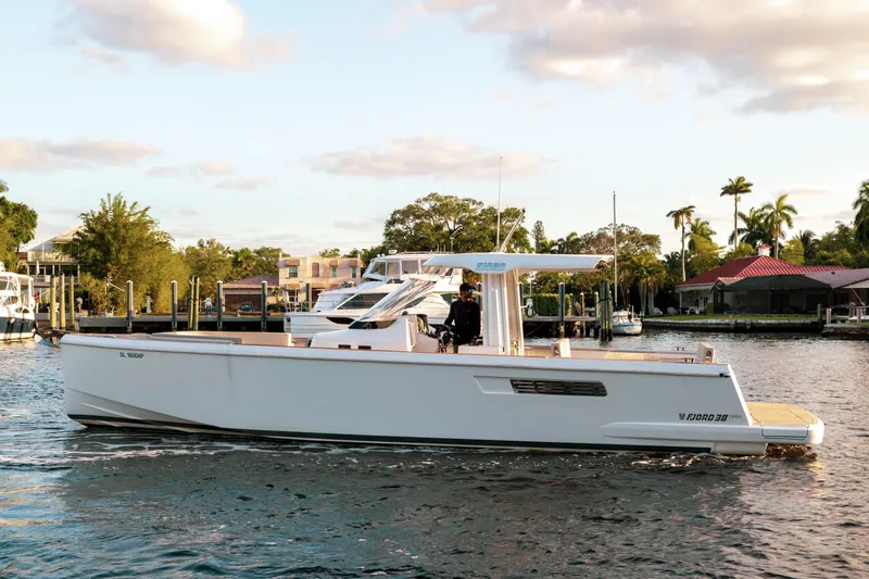 Next Yacht Photos Pics 2022 Fjord 38 Open yacht cruising on a sunny day near waterfront homes.