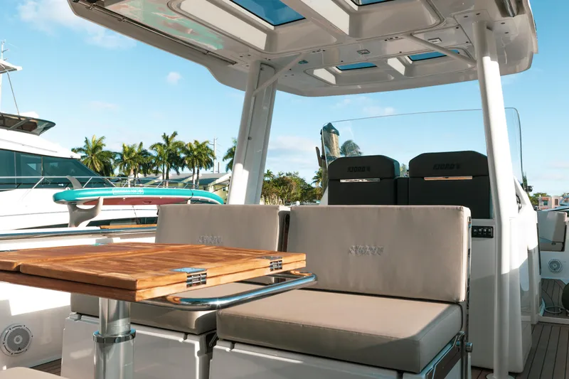 Next Yacht Photos Pics 2022 Fjord 38 Open yacht interior with seating and table, docked under clear skies.