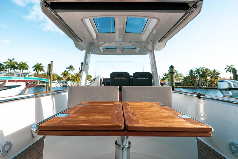 Next Yacht Photos Pics Fjord 38 Open 2022 boat with wooden table, docked near palm trees.