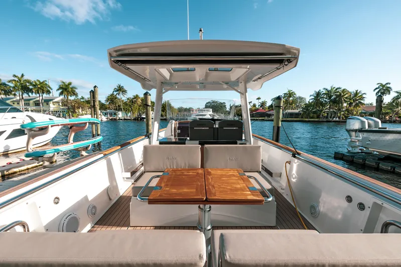 Next Yacht Photos Pics 2022 Fjord 38 Open yacht with spacious deck and seating, docked by palm trees.