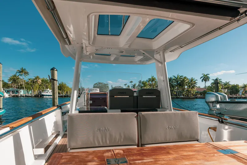 Next Yacht Photos Pics 2022 Fjord 38 Open boat interior with sunroof, docked by palm trees and clear blue sky.