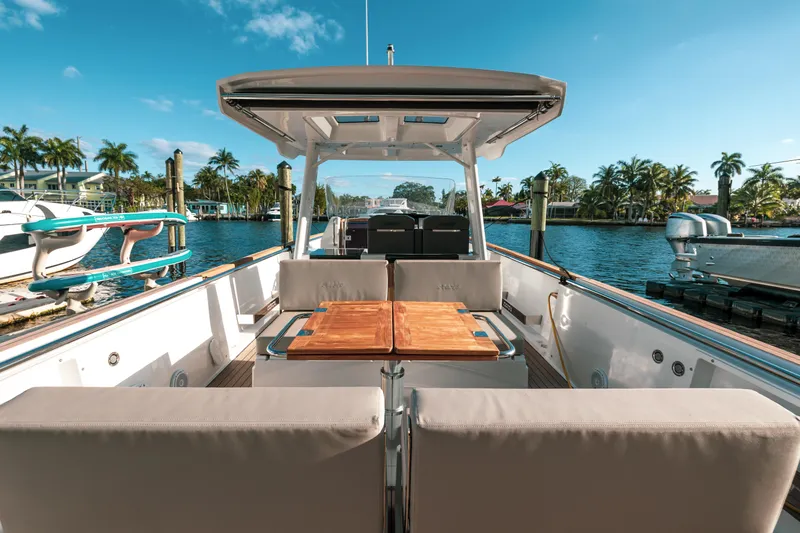 Next Yacht Photos Pics 2022 Fjord 38 Open yacht with spacious deck, docked by palm trees under clear blue sky.