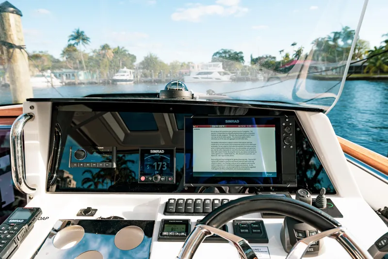 Next Yacht Photos Pics 2022 Fjord 38 Open yacht dashboard with navigation screens and steering wheel, cruising on a sunny day.
