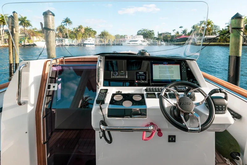Next Yacht Photos Pics 2022 Fjord 38 Open yacht helm with modern navigation equipment, docked by a scenic waterfront.