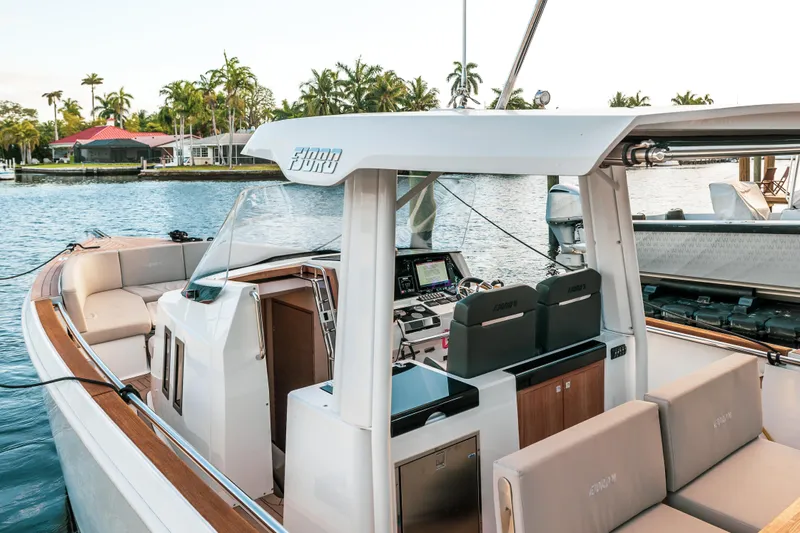 Next Yacht Photos Pics 2022 Fjord 38 Open yacht interior with modern seating and controls, docked by the water.