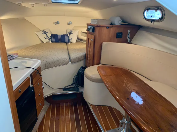  Yacht Photos Pics 2007 Pursuit OS 335 cabin interior with cozy seating, wooden table, and compact kitchen area.