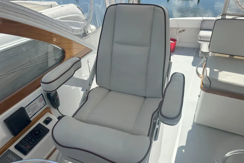 At Last 10 Yacht Photos Pics Captain's chair on 2017 Fortier F-30 Hardtop boat, featuring white upholstery and armrests.