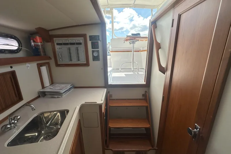 At Last 10 Yacht Photos Pics Interior of 2017 Fortier F-30 Hardtop boat with sink, stairs, and control panel.