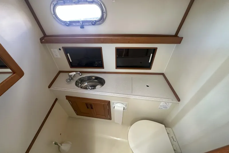 At Last 10 Yacht Photos Pics 2017 Fortier F-30 Hardtop boat bathroom with sink, toilet, and porthole window.