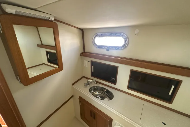 At Last 10 Yacht Photos Pics 2017 Fortier F-30 Hardtop interior with sink, mirror, and porthole window.