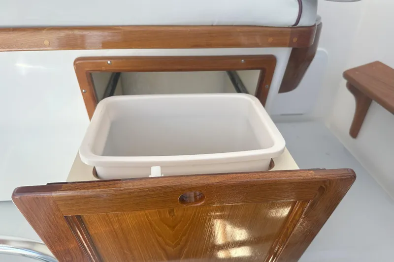 At Last 10 Yacht Photos Pics Wooden storage compartment with white bin in 2017 Fortier F-30 Hardtop boat interior.