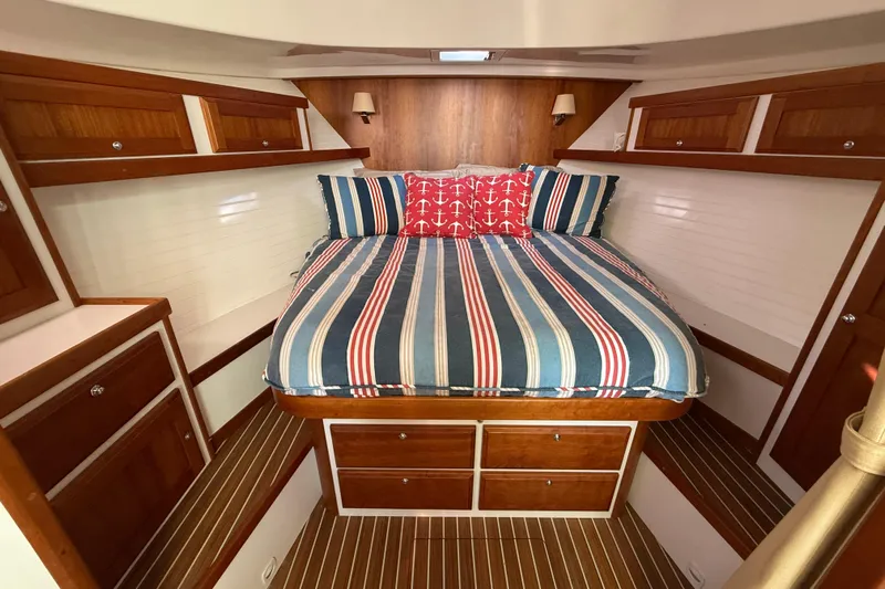 Never Say Never Again Yacht Photos Pics 2019 Back Cove Downeast 37 cabin with striped bedding and wooden cabinetry.