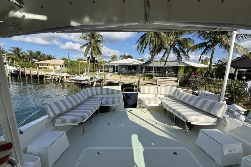 Never Say Never Again Yacht Photos Pics 2019 Back Cove Downeast 37 yacht with spacious deck and striped seating, docked by palm trees.