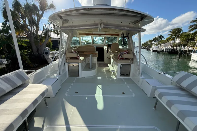 Never Say Never Again Yacht Photos Pics 2019 Back Cove Downeast 37 boat interior with seating, docked by palm trees.