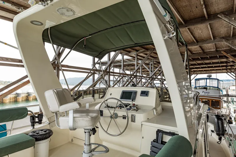 Greymalkin II Yacht Photos Pics 2008 North Pacific 39 Pilothouse helm with steering wheel and navigation equipment under canopy.