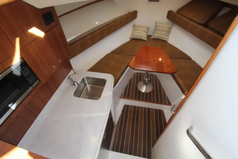 Mary Michele Yacht Photos Pics 2022 Albemarle 30 Express cabin interior with kitchenette, seating, and wooden table.