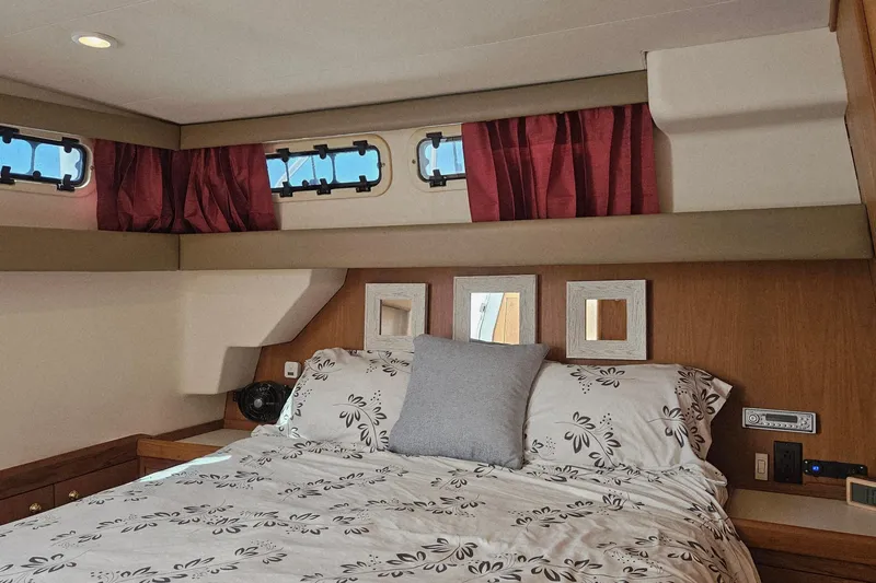  Yacht Photos Pics Cozy bedroom interior of 1999 Mainship 430 Trawler with floral bedding and red curtains.