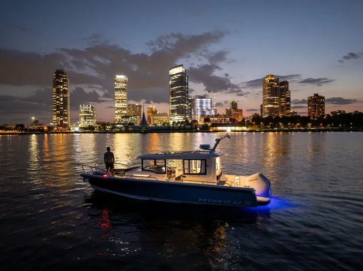  Yacht Photos Pics Nimbus Commuter 9 boat on water at dusk, city skyline in background, 2025 model.