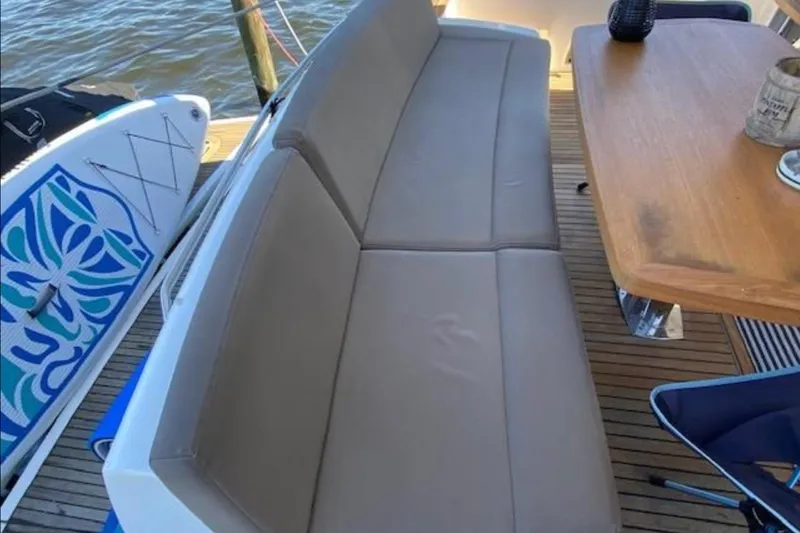  Yacht Photos Pics Outdoor seating and table on a 2012 Prestige 500 yacht deck, with paddleboard nearby.