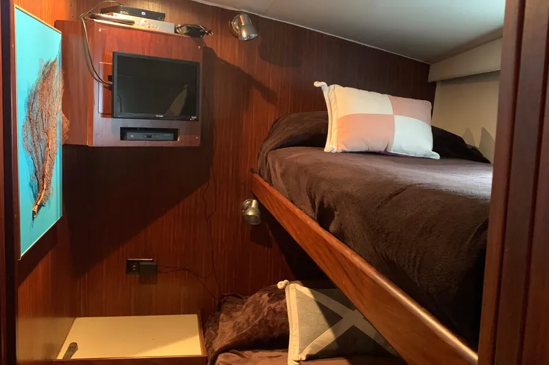  Yacht Photos Pics Cozy cabin interior of 1984 Hatteras 52 Convertible with bunk beds and wall-mounted TV.