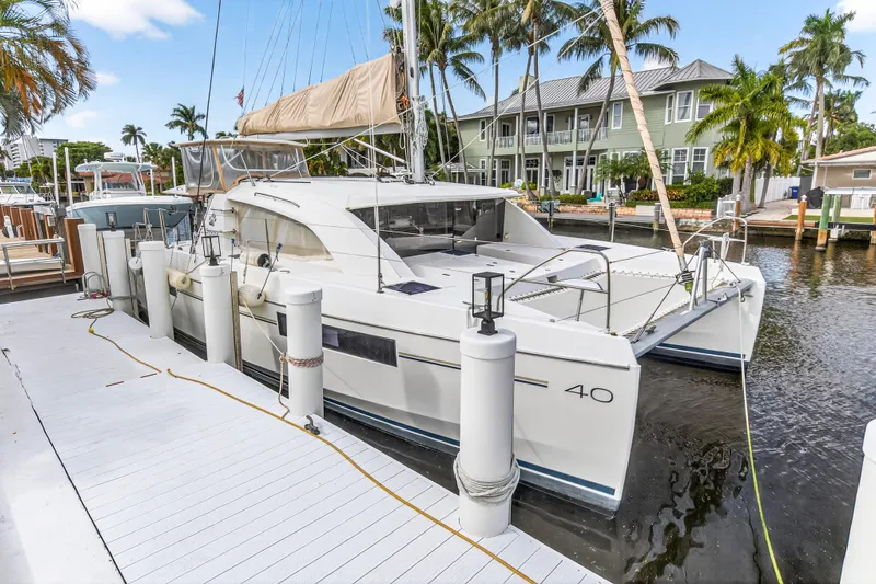 Yacht Photos Pics 2017 Leopard 40 catamaran docked by waterfront homes, surrounded by palm trees.